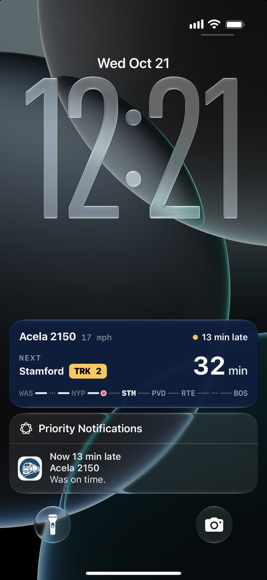 A TrackWatch Live Activity on the iPhone Lock Screen: Acela 2150, next stop Stamford on Track 2 in 32 minutes, 13 minutes late, with its route line, and below it the alert that the train is now 13 minutes late